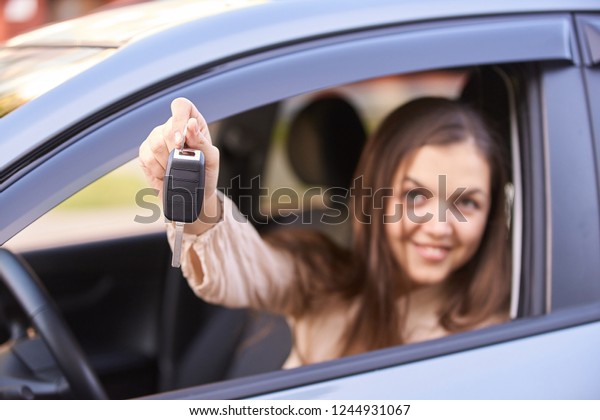 Young woman in car. Ride instruction. Automobile\
loan. Hand with key.
