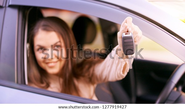 Young woman in car. Ride instruction. Automobile\
loan. Hand with key.