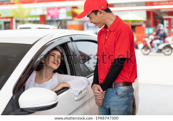 young woman in the car, talking to worker for\
refueling gasoline at the gas\
station