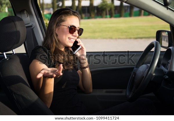A young\
woman in the car talks on the smart\
phone