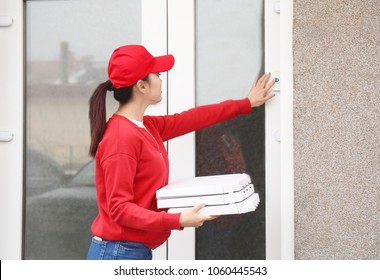 Young Woman With Cardboard Pizza Boxes Ringing Doorbell Outdoors. Food Delivery Service