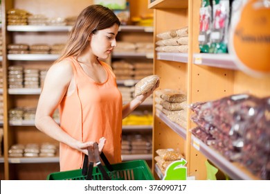 Young Woman Carrying A Basket And Reading A Product Label At A Grocery Store