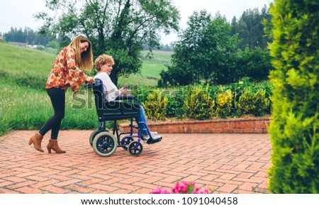 Woman carrying her mother in a wheelchair