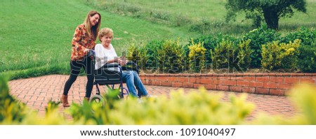 Woman carrying her mother in a wheelchair