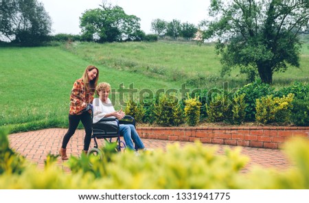 Similar – Woman carrying her mother in a wheelchair