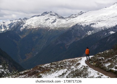 Young Woman Carrying Orange Backpack Stands And Admires Panoramic View On Cascade Pass Trail , North Cascades National Park, WA, USA. Concept Of Solo Female Traveler.