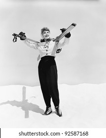 Young woman carrying ski and ski pole on her shoulders