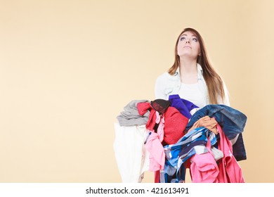 Young Woman Carrying Stack Pile Of Dirty Laundry Clothes. Girl Cleaning Tidying In Studio.