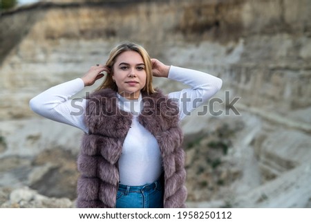 Young woman with casual cloth and fur coat, outdoor shoot near sand rocks. summer vacation