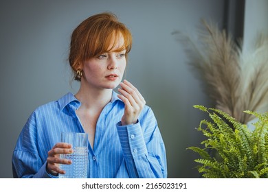 Young Woman In Casual Clothes At Home Near Window Holding Pill And Glass Of Fresh Water. Headaches, Depression, Medicine Supplements Vitamins, Sedatives, Menopause