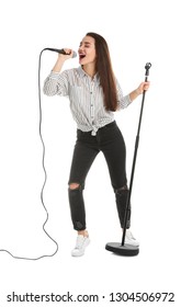 Young woman in casual clothes singing with microphone on white background
