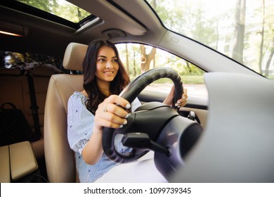 Young Woman In Casual Wear Looking Over Her Shoulder While Driving A Car