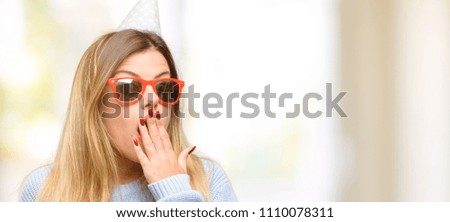 Young woman celebrates birthday covers mouth in shock, looks shy, expressing silence and mistake concepts, scared