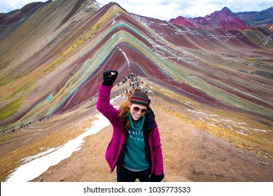 Young woman celebrating with the fist held high, after a long tracking through Vinicunca (rainbow mountain) Perú.