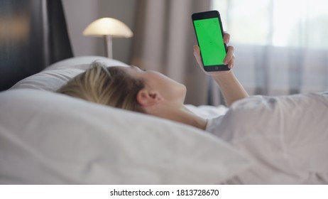 Young Woman With Cell Phone On Bed, Shoulder View. Technology Addiction. Green Screen Phone.