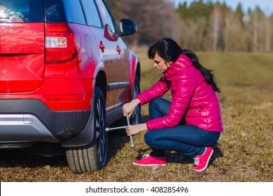 Young Woman Changing The Punctured Tyre On His Car