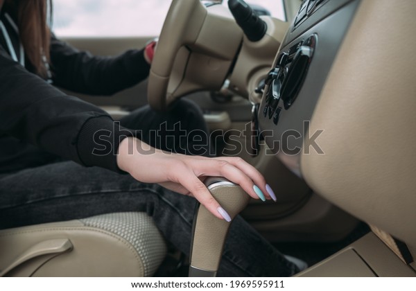Young woman changing speed by hand holding\
gearbox in car. Woman driver shifting gears and driving a car.\
European girl driving a car moving transmission shifting automatic\
transmission.