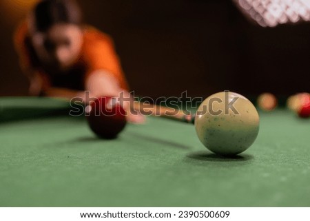 Young woman chasing billiard balls on a spacious table in the billiard room, close-up. Billiards concept. Copy space