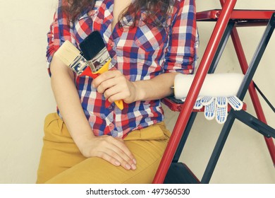 Young woman in checkered shirt with different instruments. Painter master in the room. Women's hands with brushes. - Powered by Shutterstock