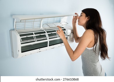 Young Woman Checking Air Conditioner In House