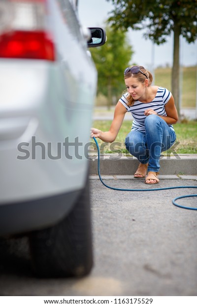 Young
woman checking the car tyre pressure - inflating
it