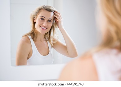 Young Woman Checking Her Hair In Bathroom Mirror At Home