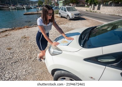 A Young Woman Is Checking Her Map While Parked By The Sea On The Greek Island