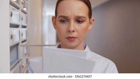 Young Woman Checking Mailbox And Feeling Irritated Receiving Bad News. Close Up Portrait Of Female Tenant Opening Postbox And Taking Refusal Notification In Apartment Lobby