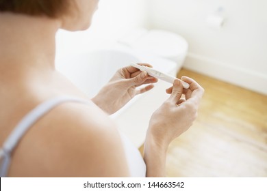 Young Woman Checking Pregnancy Test Kit In Bathroom