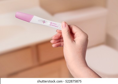 Young Woman Checking Pregnancy Test Kit In Bathroom