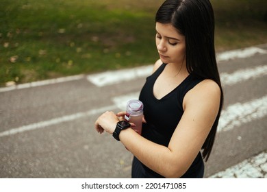 Young Woman Checking Progress On Smart Watch. Female Runner Looking At Smart Watch Heart Rate Monitor