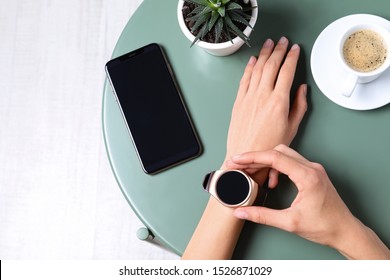 Young woman checking smart watch at green table, top view - Powered by Shutterstock