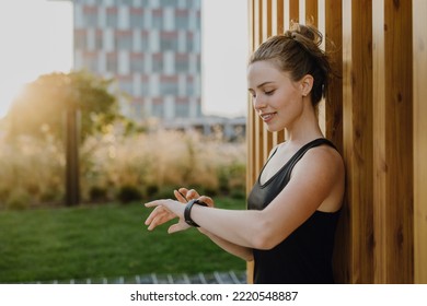 Young woman checking smartwatch in city, preparing for run, healthy lifestyle and sport concept. - Shutterstock ID 2220548887