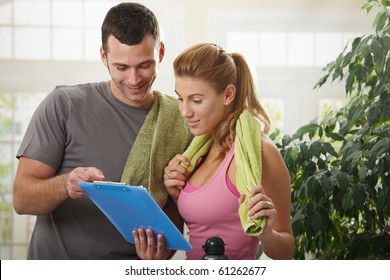 Young Woman Checking Training Plan With Her Personal Trainer At Home.