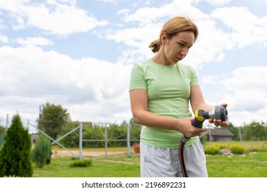 Young Woman Checking Water Pressure In Garden Hose Before Sowing Lawn