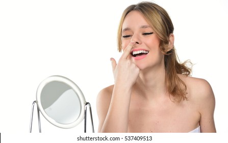 young woman checks her nose in the mirror