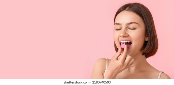 Young woman with chewing gum on pink background with space for text
