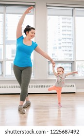 Young woman with child doing workout dancing in gym class to loose baby weight. Child-friendly fitness for mothers with kids toddlers. Lifestyle concept of parent activity. 