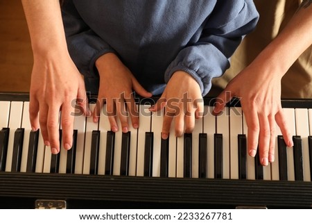 Young woman with child playing piano, above view. Music lesson