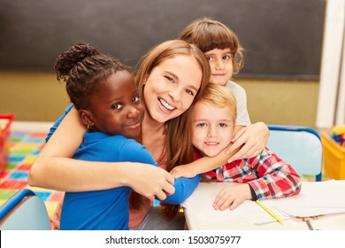 Young woman as a childminder or teacher hugs children in daycare or elementary school