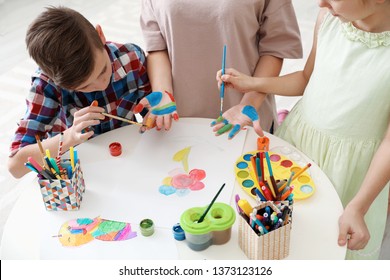 Young woman with children painting hands at table indoors, closeup view - Shutterstock ID 1373123126