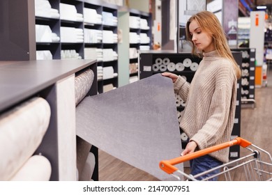 Young Woman Choose Wallpaper In Hardware Store. Home Design And Renovation Concept