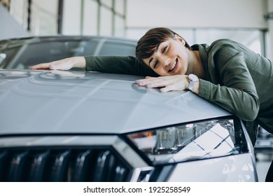 Young woman choosimng a car in a car showroom