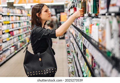 Junge Frau, die sich in einem Supermarkt für Pflegeprodukte entscheidet