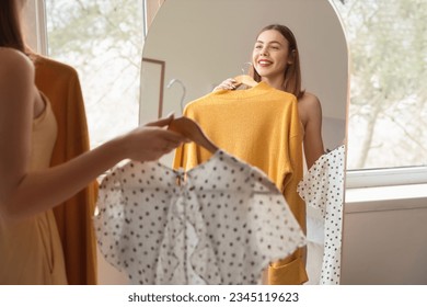 Young woman choosing clothes in front of mirror at home - Powered by Shutterstock