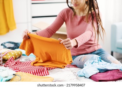 Young woman choosing clothes in her bedroom and organizing her wardrobe