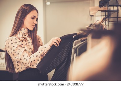 Young woman choosing clothes on a rack in a showroom  - Powered by Shutterstock