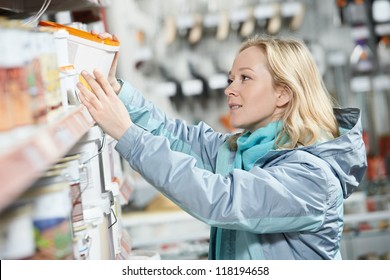 Young Woman Choosing Color Paint During Hardware Shopping In Home Improvement Store Supermarket