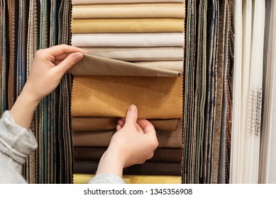 Young Woman Choosing Fabric For New Curtains In Shop