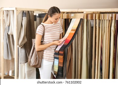 Young Woman Choosing Fabric For New Curtains In Shop